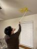 After completing the air leakage tests, the energy rater uses a broom handle to remove the register-sealing tape.