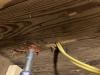 The electrical conduit (metal) on the left has been sealed to the subfloor using fire-rated caulk, while the penetration for the yellow electrical wire on the right has not been air-sealed yet.