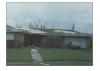 Failure of extruded concrete flat tile roofing due to bond failure between tile, mortar, and underlayment resulting from hurricane force winds.