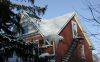 The icicles and the bare spot along the left roof ridge indicate that heat from the second-story room may be heating the underside of the roof deck, melting the snow and likely leading to ice dam formation.