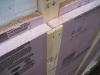 This close-up of an exterior wall retrofit of a masonry brick home shows the fluid-applied water and air control layer (white), 2x4 furring strips and two layers of rigid foam insulation (pink), then 1x4 furring which provides a ventilation gap