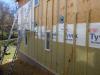 Holes in the exterior walls are flashed and flashing is integrated with housewrap before installing rigid mineral wool insulation.