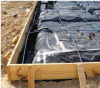 This Texas homes uses a slab foundation including a 4-in.-thick post-tensioned monolithic slab with turned-down edges poured over a 6-mil polyethylene vapor barrier and capillary break; slab edge insulation is not used due to termite risk.