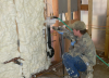 An installer fills these wall cavities with spray foam insulation, which will be trimmed flush with the stud faces after it dries and hardens.