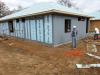 A water-resistant membrane that takes the place of house wrap is sprayed is painted over seams and window framing then sprayed over the entire wall to provide a weather-resistant air barrier.