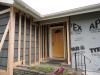Ledger board, metal brackets, and vertical 2x4s have been installed in preparation for exterior spray foam in this retrofit exterior wall insulation technique