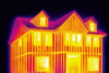 Thermal bridging or heat transfer through wall framing is seen in this infrared camera image, with yellow at windows and wall framing indicating areas with the most heat transfer and darker areas indicating less heat transfer due to insulation