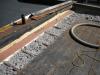 Roofing paper protects the top of the new plywood parapet while the base of the parapet is air sealed with spray foam and fibrous insulation is installed in the rafter cavities in this flat roof retrofit