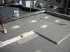 The wood blocking for future PV panel installation extends above the surface of the top layer of polyisocyanurate rigid foam insulation installed as part of a flat roof retrofit