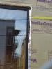 Wrong - House wrap tape is not fully adhered at seam and flashing tape is missing from window head, jamb, and corner above window.