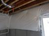 Wrong - This plastic-covered blanket insulation is not perforated, does not cover the entire basement wall, is not sealed at the edges, and is not installed over rigid foam.