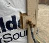Wrong - House wrap was not cut installed under the plumbing hose bib trim and/or edges of the house wrap have not been taped so sheathing is exposed.